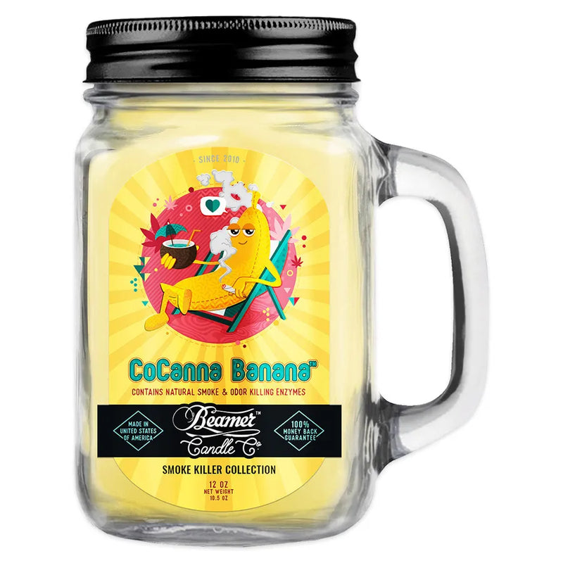 Beamer Candle co 12oz candle in the CoCanna Banana scent. Yellow-beige wax, reusable glass mason jar with metal lid. Yellow Beamer branded sticker with a banana sitting and enjoying a pina colada.