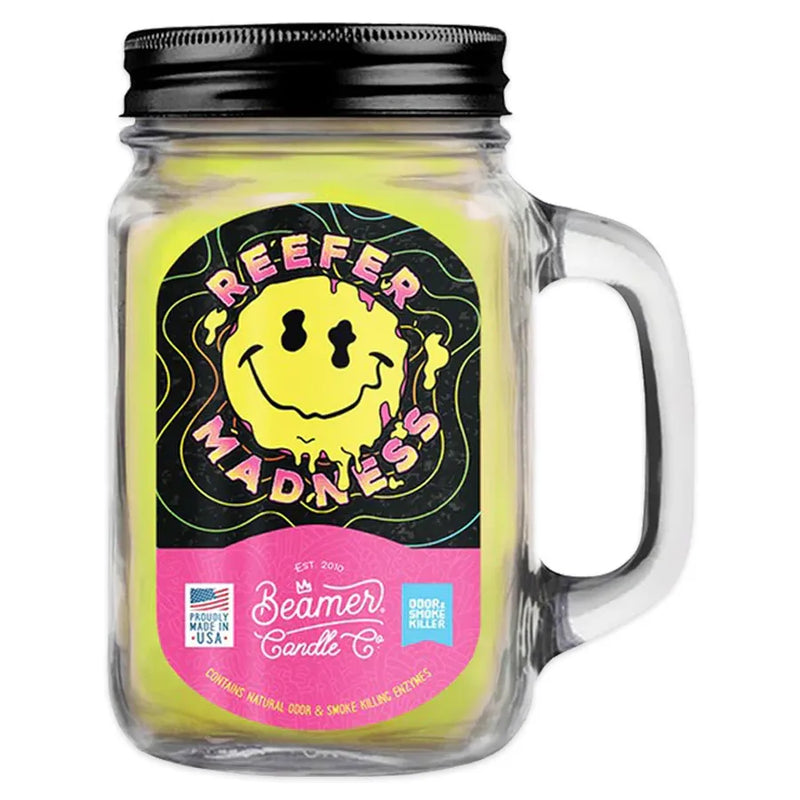 Beamer Candle co's 12oz candle in the reefer madness scent. Yellow wax, reusable glass mason jar with a metal lid. Beamer branded sticker features a melting smiley face with the words reefer madness around it.
