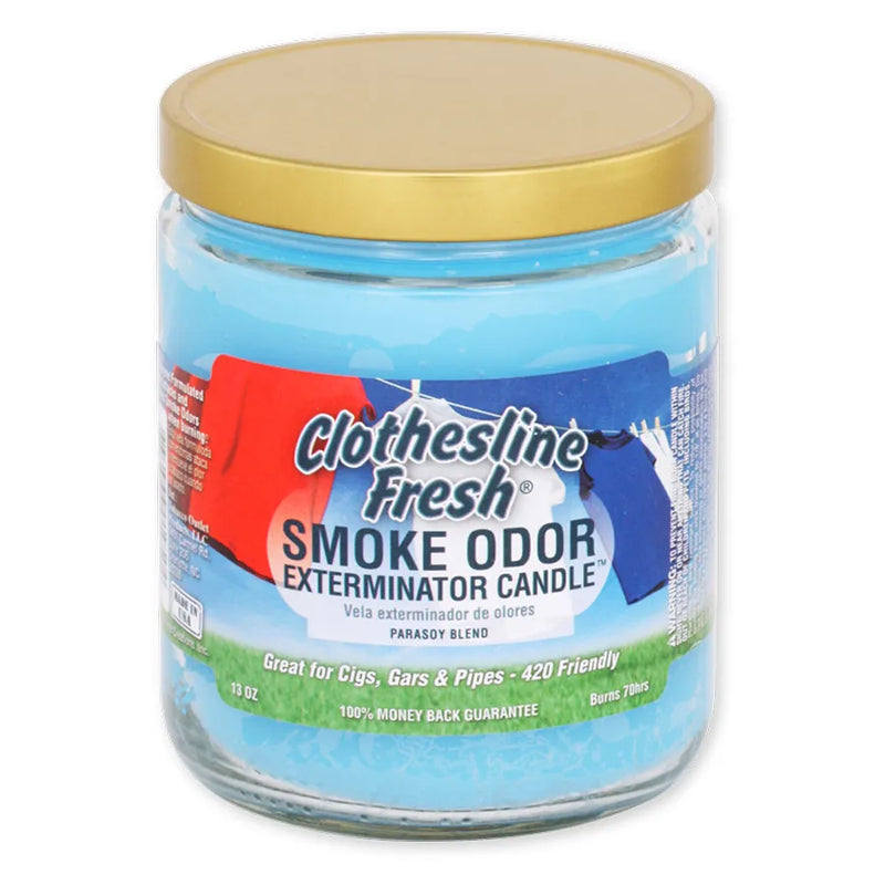 Smoke Odor's 13oz Exterminator Candle in the Clothesline Fresh scent. A baby blue wax colour, gold lid and a sticker label that shows a bright blue sky, green grass, and a clothesline with blue white and red t-shirts hung.