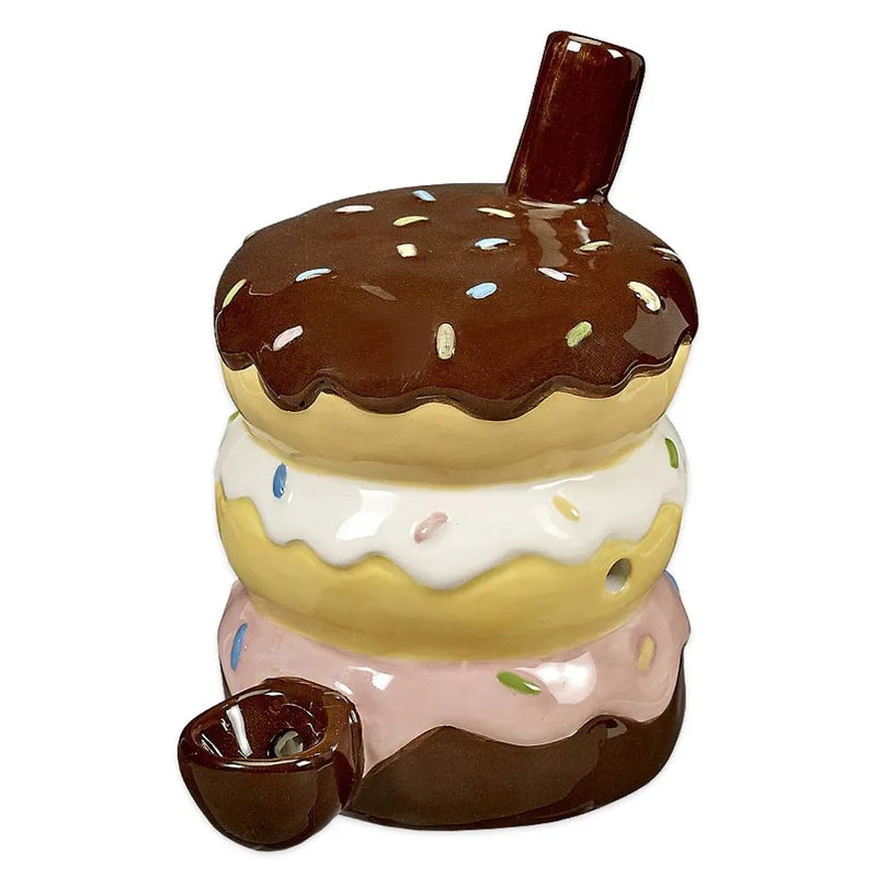 A ceramic smoking pipe in the shape of three donuts stacked on top of eachother. A chocolate covered donut on top, vanilla covered donut in the middle, and a strawberry covered donut on the bottom.