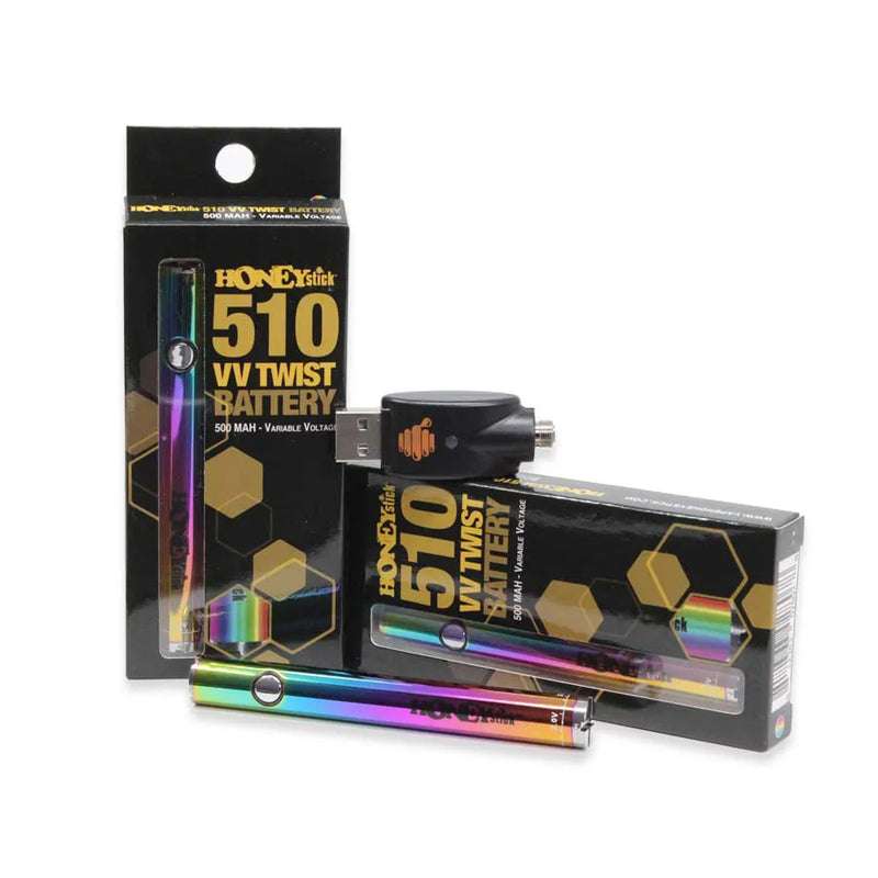 Honeystick's 510 thread rainbow vape cartridge battery. Laying next to two display boxes that showcase the retail packaging and the usb charger sits on top.