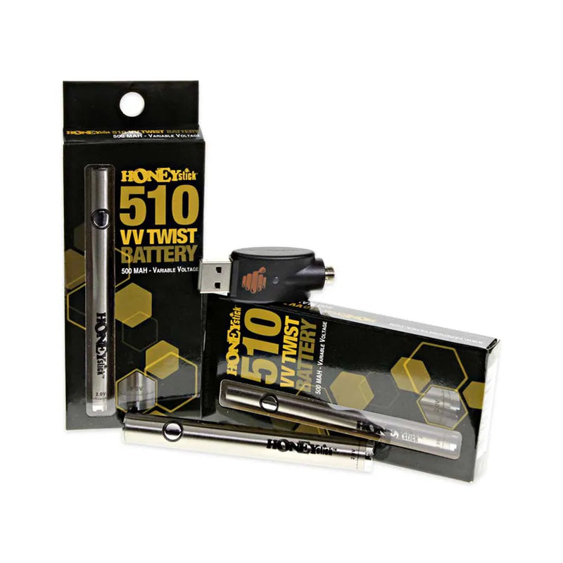 Honeystick's 510 thread silver vape cartridge battery. Laying next to two display boxes that showcase the retail packaging and the usb charger sits on top.