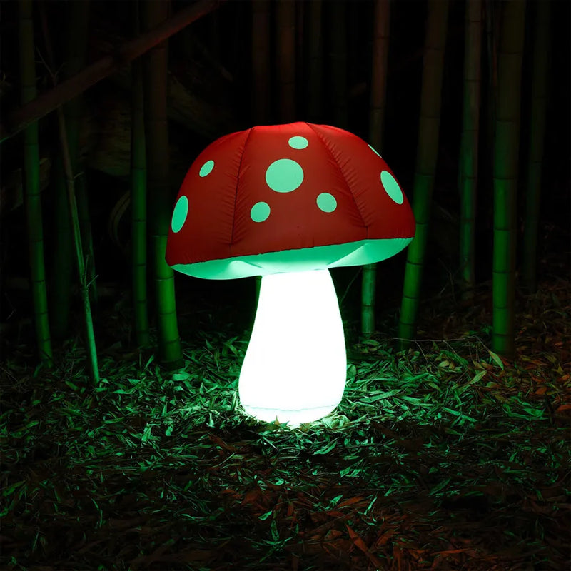 Pulsar's inflatable mushroom with an led light. 3 foot length. A white stemmed mushroom with a red cap with white polka-dots. The inflatable mushroom is in a dark forest and lit up green by the LED light.